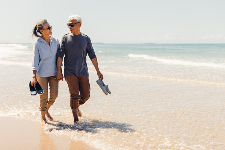 senior couple walkin gon beach